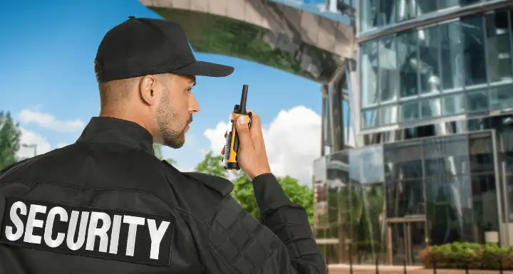 Security officer using a two-way radio outside a glass office building
