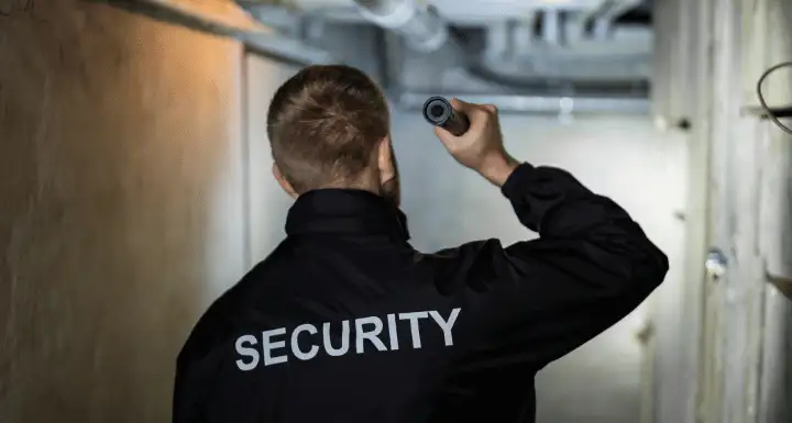 Security officer shining a flashlight in a dark basement corridor