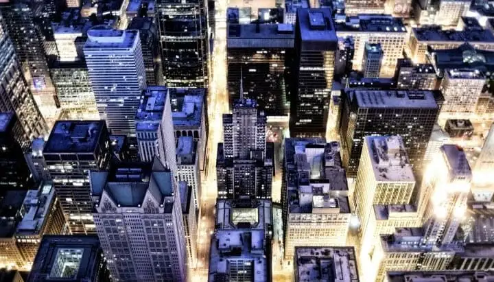 Aerial night view of a dense city with lit streets and rooftops